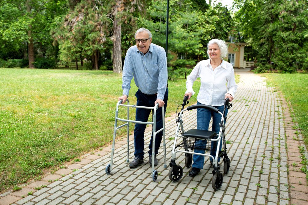 Senioren mit Gehhilfe machen einen Spaziergang im Park Gehhilfe